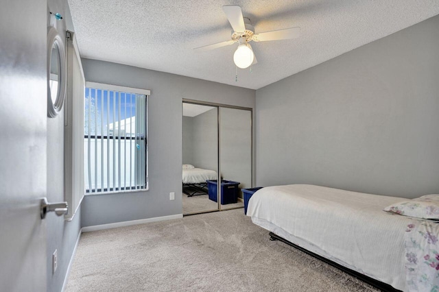 bedroom featuring ceiling fan, light colored carpet, a textured ceiling, and a closet