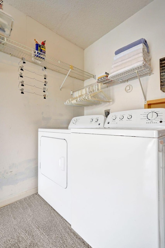 washroom featuring carpet floors, washing machine and dryer, and a textured ceiling