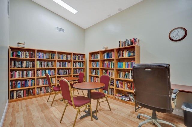 office space featuring high vaulted ceiling and light hardwood / wood-style floors