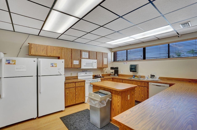 kitchen featuring sink, white appliances, kitchen peninsula, a drop ceiling, and light wood-type flooring