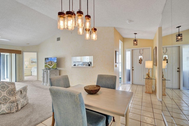 tiled dining room featuring lofted ceiling, a textured ceiling, and plenty of natural light