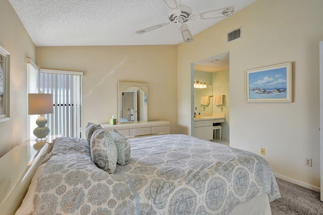 bedroom with ceiling fan, connected bathroom, carpet floors, and a textured ceiling