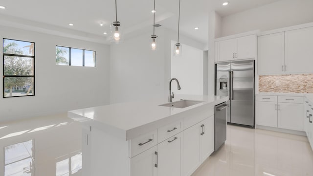 kitchen with appliances with stainless steel finishes, pendant lighting, white cabinets, decorative backsplash, and a center island with sink