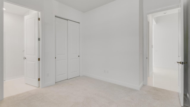 unfurnished bedroom with light colored carpet and a closet