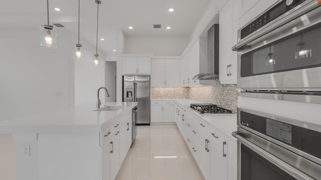 kitchen with white cabinets, decorative light fixtures, sink, and wall chimney exhaust hood