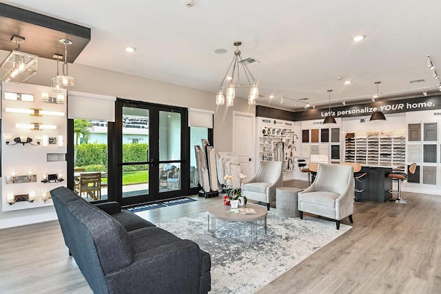 living room featuring wood-type flooring, track lighting, bar area, and french doors