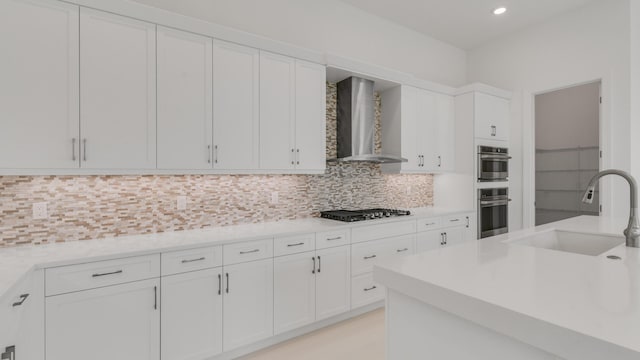 kitchen featuring gas stovetop, white cabinetry, sink, and wall chimney exhaust hood