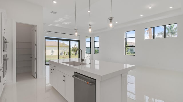 kitchen with a wealth of natural light, decorative light fixtures, white cabinetry, sink, and stainless steel appliances