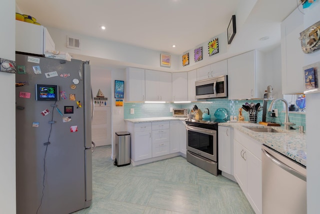 kitchen with white cabinetry, stainless steel appliances, sink, and tasteful backsplash