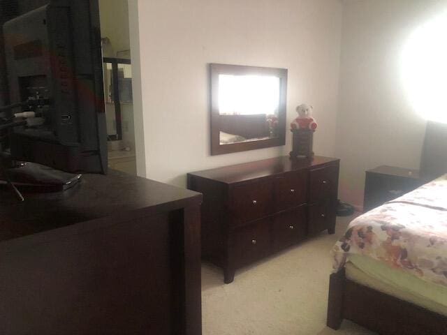 bedroom featuring ensuite bath and light colored carpet