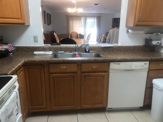 kitchen with a chandelier, sink, light tile patterned floors, and white appliances