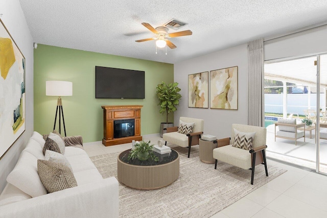 living room with ceiling fan, light tile patterned floors, and a textured ceiling