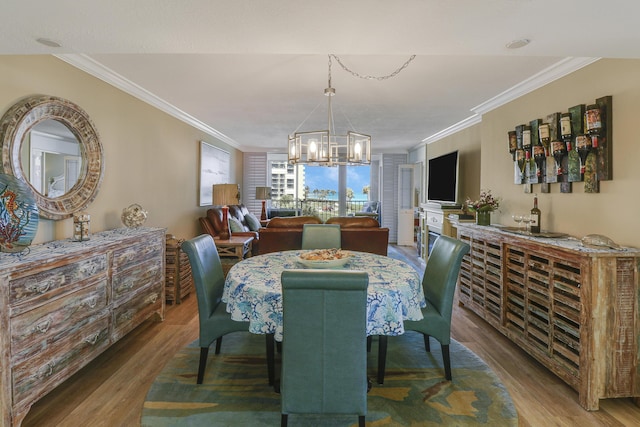 dining room featuring a notable chandelier, ornamental molding, and hardwood / wood-style floors