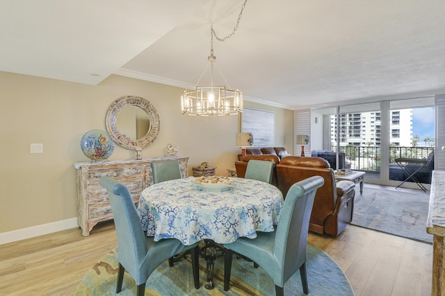 dining room with expansive windows, an inviting chandelier, crown molding, and light hardwood / wood-style floors