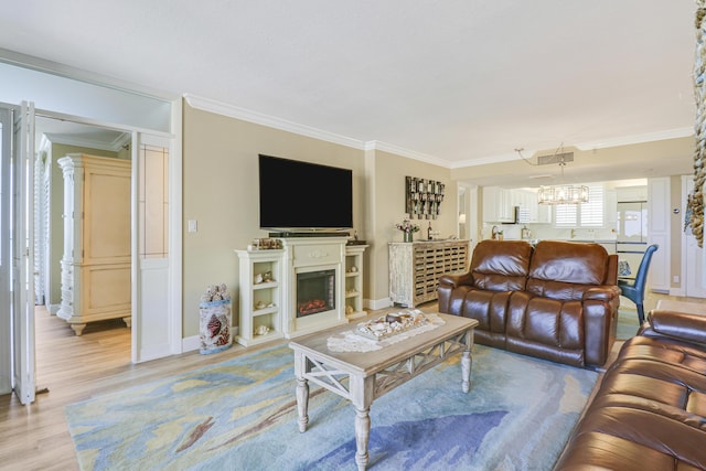 living room with ornamental molding, a chandelier, and light hardwood / wood-style floors