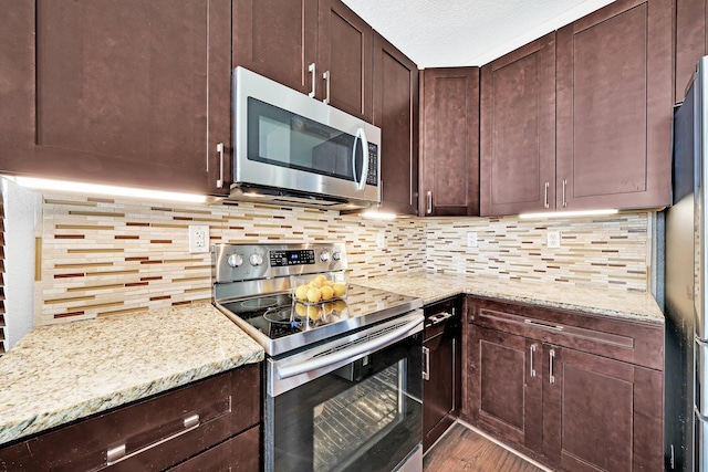 kitchen with light stone counters, hardwood / wood-style flooring, tasteful backsplash, and appliances with stainless steel finishes