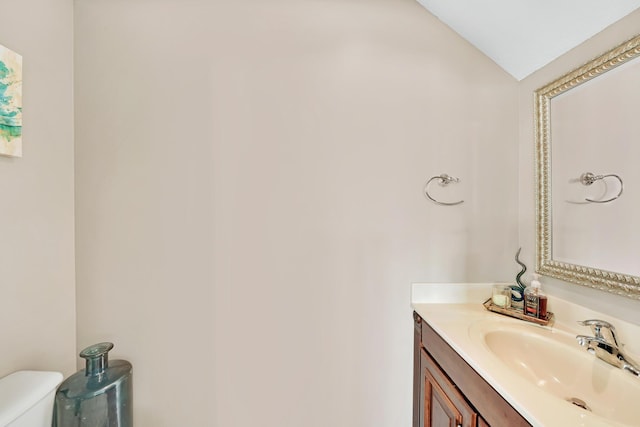 bathroom with vanity, lofted ceiling, and toilet