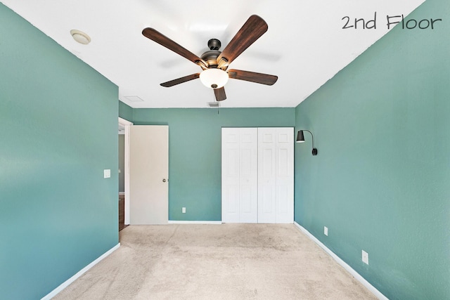 unfurnished bedroom featuring light carpet, ceiling fan, and a closet