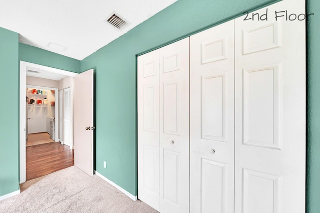 unfurnished bedroom with light colored carpet and a closet