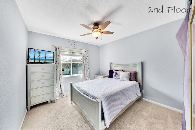 bedroom with ceiling fan, light colored carpet, and a textured ceiling