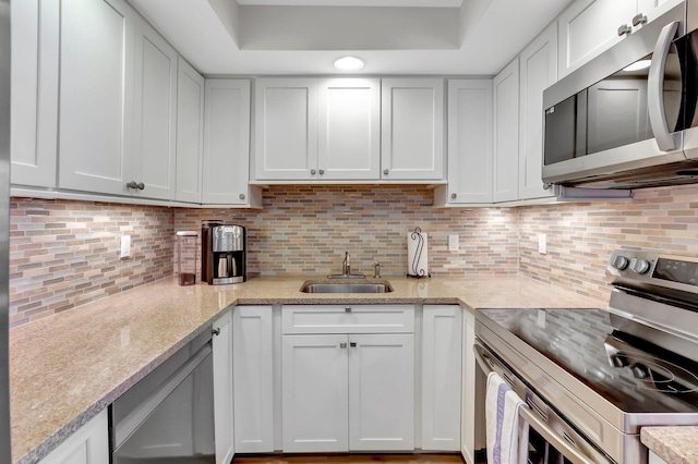 kitchen featuring stainless steel appliances, sink, white cabinets, and decorative backsplash