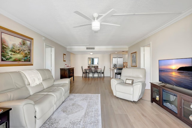 living room featuring ornamental molding, a textured ceiling, ceiling fan, and light wood-type flooring