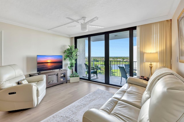 living room with crown molding, a wall of windows, ceiling fan, light hardwood / wood-style floors, and a textured ceiling