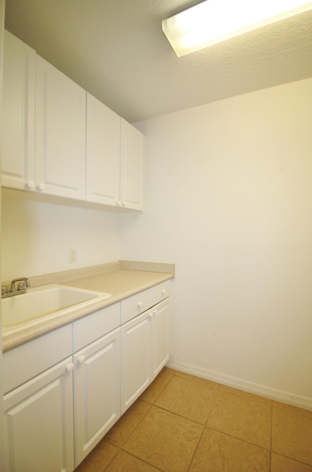 kitchen with sink, white cabinets, and light tile patterned flooring