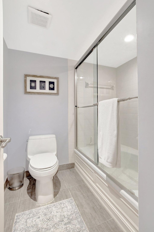 bathroom with tile patterned floors, enclosed tub / shower combo, and toilet