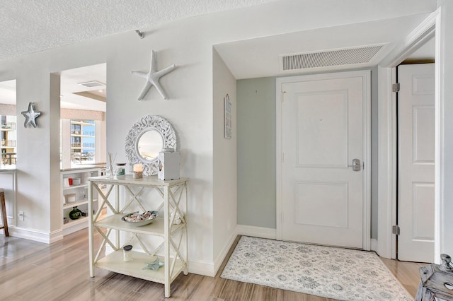 foyer entrance with light hardwood / wood-style flooring and a textured ceiling