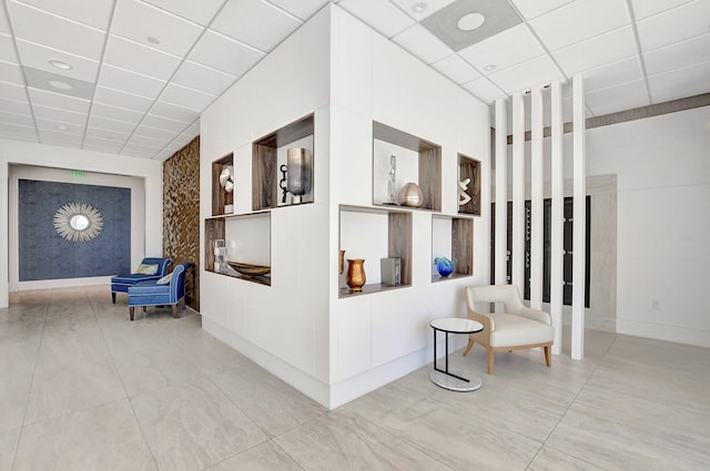 corridor featuring a drop ceiling and light tile patterned floors