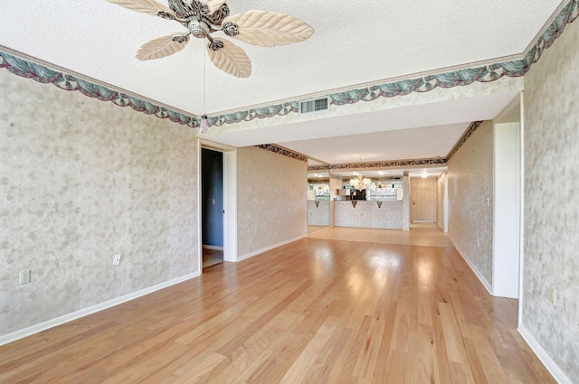 unfurnished living room with hardwood / wood-style flooring, ceiling fan, ornamental molding, and a textured ceiling