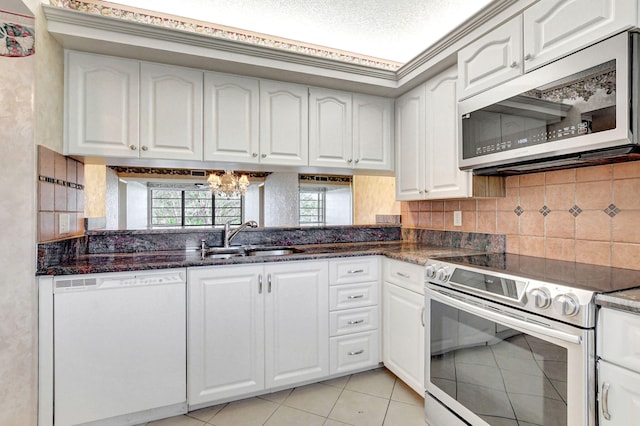 kitchen featuring sink, white cabinetry, stainless steel appliances, decorative backsplash, and dark stone counters