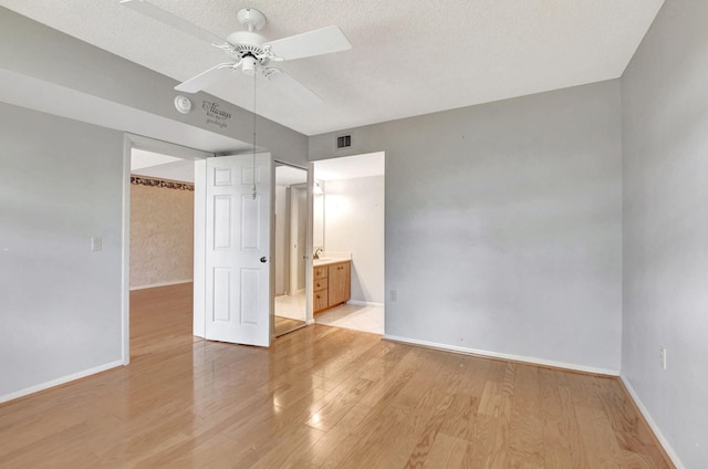 unfurnished bedroom with sink, ceiling fan, ensuite bathroom, light hardwood / wood-style floors, and a textured ceiling