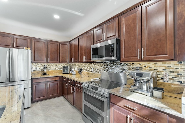 kitchen with stainless steel appliances, tasteful backsplash, light stone countertops, and light tile patterned floors