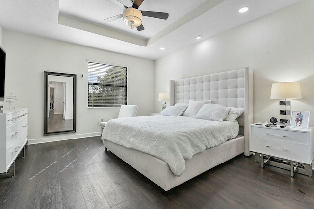 bedroom featuring ceiling fan, dark hardwood / wood-style flooring, and a raised ceiling