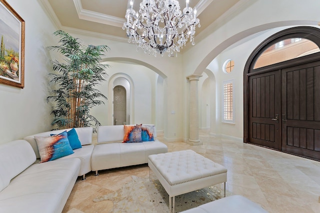 interior space with ornamental molding, a tray ceiling, decorative columns, and a notable chandelier