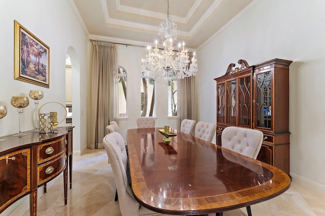 dining space with ornamental molding, a tray ceiling, and a chandelier