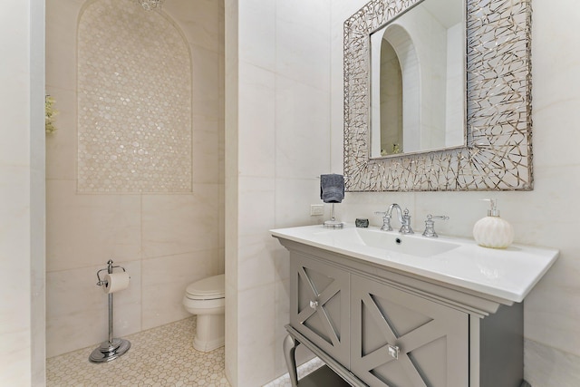 bathroom with tile walls, vanity, tile patterned flooring, and toilet