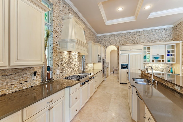 kitchen featuring sink, custom exhaust hood, crown molding, dark stone countertops, and stainless steel gas stovetop