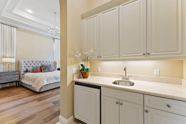 kitchen with sink, crown molding, decorative light fixtures, light wood-type flooring, and dishwashing machine