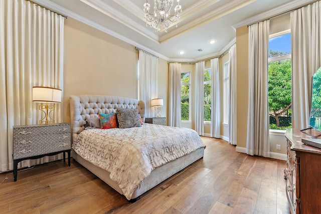 bedroom with multiple windows, wood-type flooring, ornamental molding, and a raised ceiling