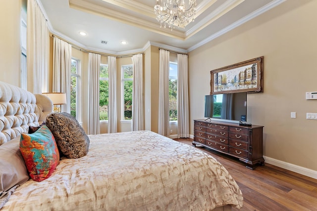 bedroom with a tray ceiling, dark wood-type flooring, ornamental molding, and a chandelier