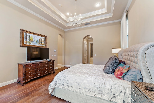 bedroom with crown molding, wood-type flooring, a raised ceiling, and a notable chandelier