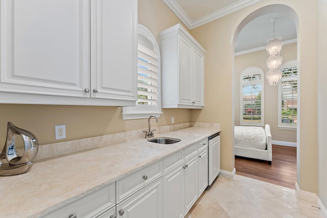 kitchen with sink, light tile patterned floors, ornamental molding, dishwasher, and white cabinets