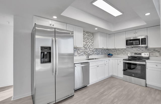 kitchen featuring a tray ceiling, stainless steel appliances, and white cabinets