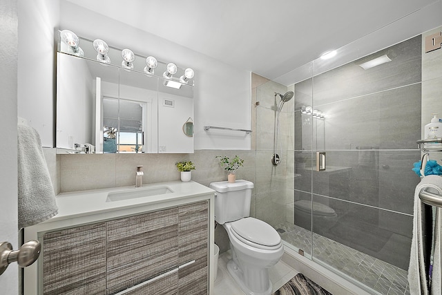 full bath featuring tile walls, a stall shower, toilet, and vanity