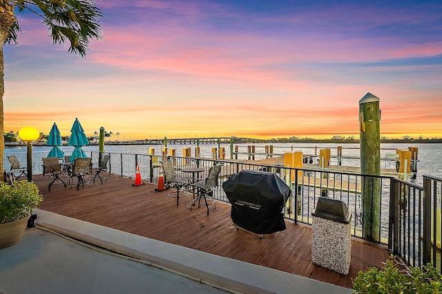 deck at dusk with a water view and grilling area