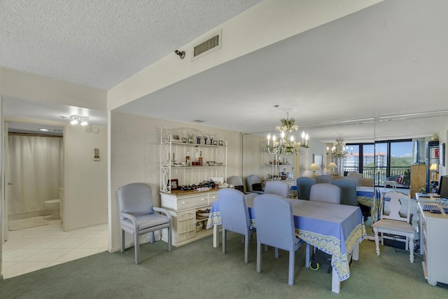 carpeted dining room with a notable chandelier and a textured ceiling