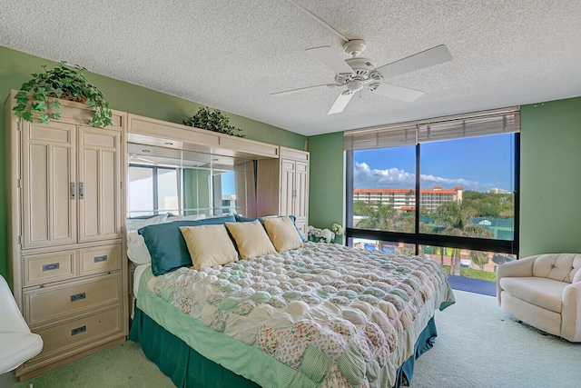 bedroom with ceiling fan, access to outside, light carpet, and a textured ceiling